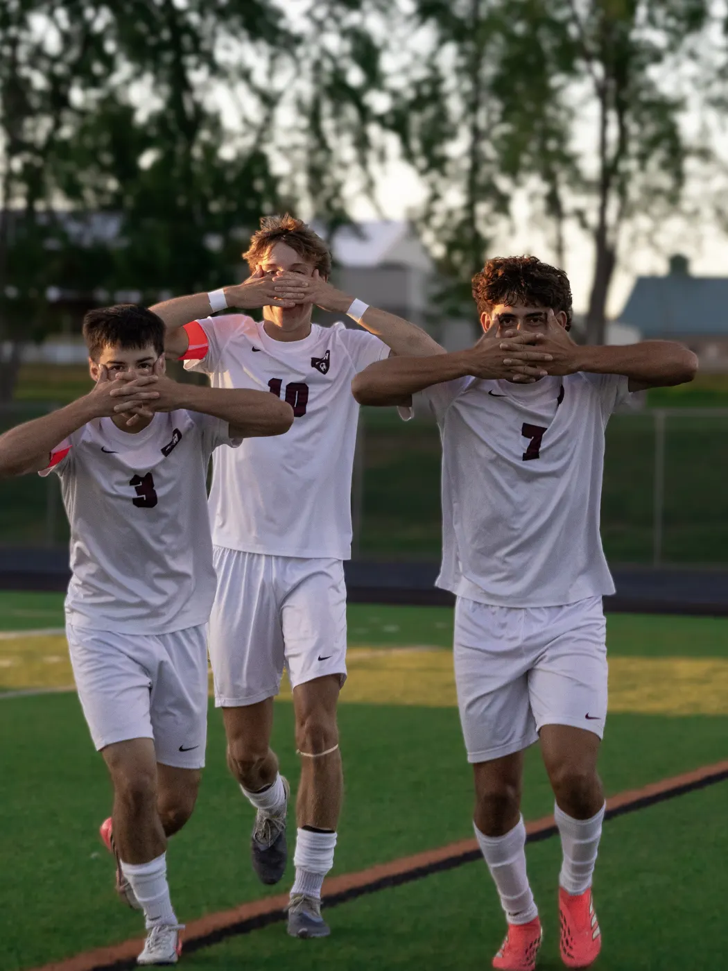 Three soccer teammates celebrating together after a goal