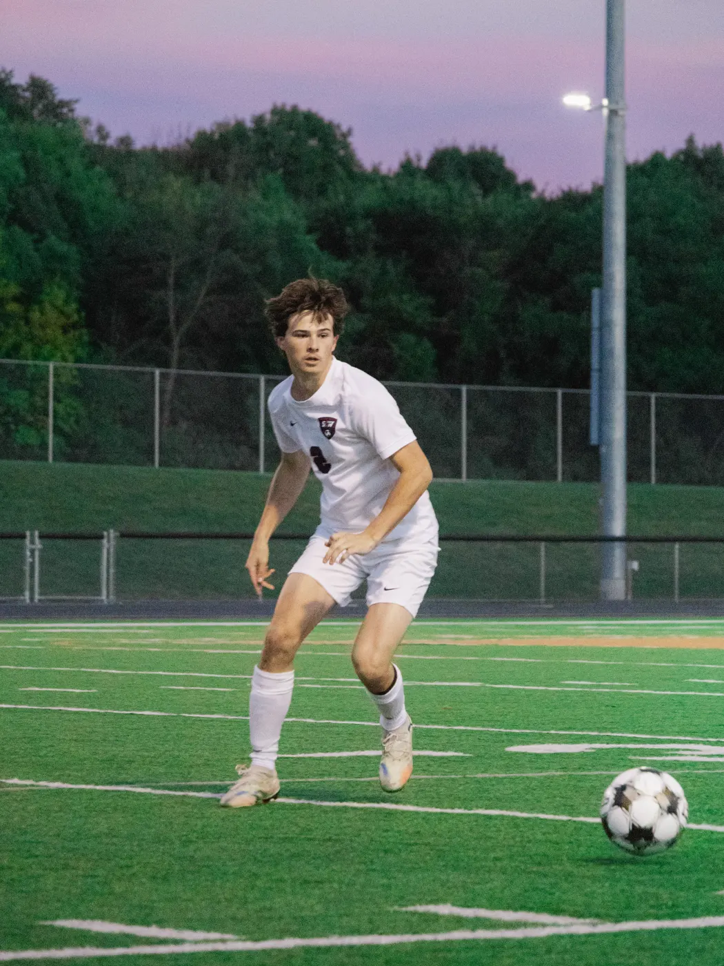 Soccer player tracking the ball under the stadium lights