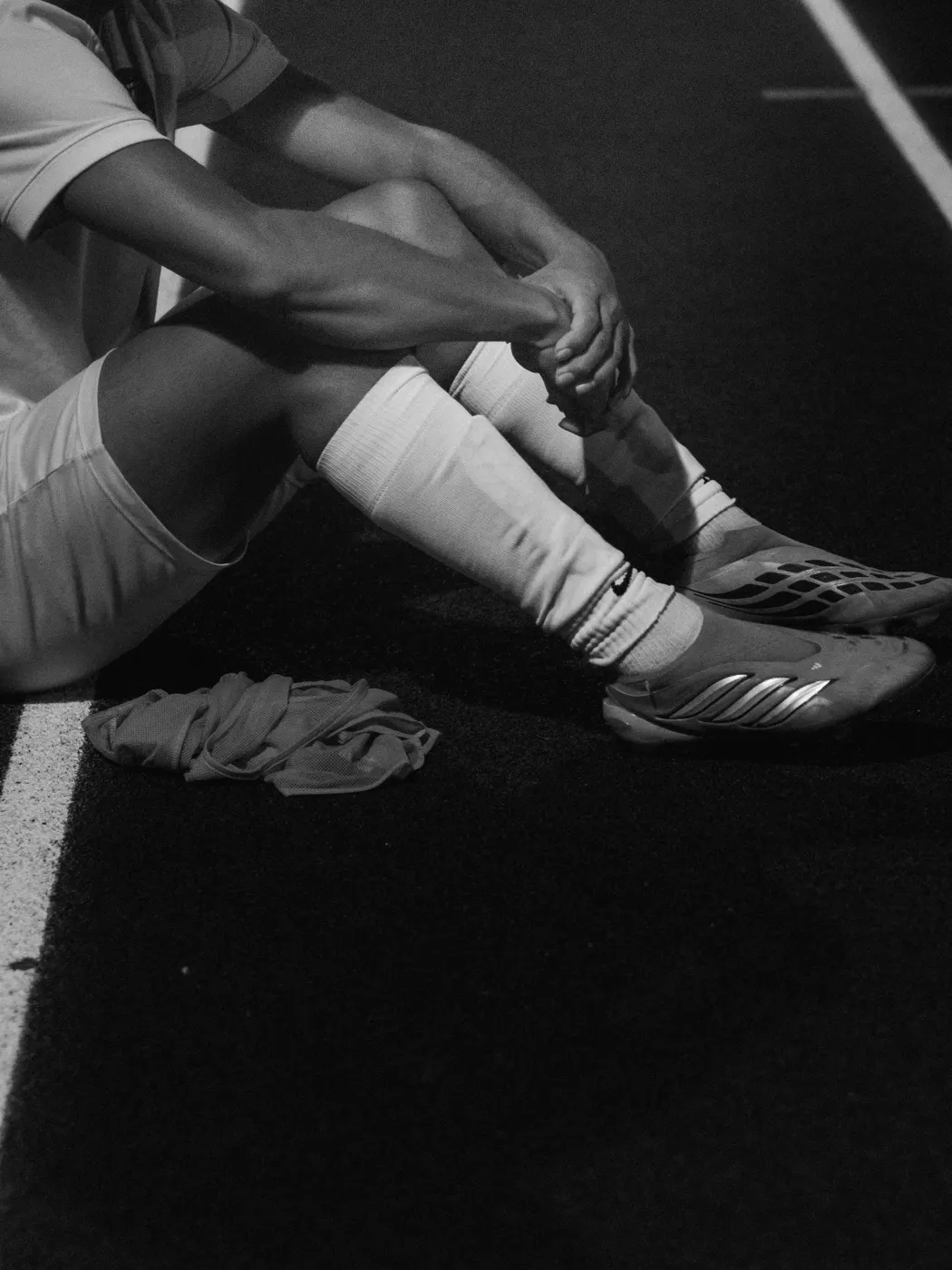 Black-and-white detail of soccer players seated together on the bench